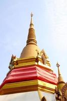 stupa dourada e céu azul claro no templo de wat pariwas, base coberta de pano vermelho de stupa, bangkok, tailândia. foto