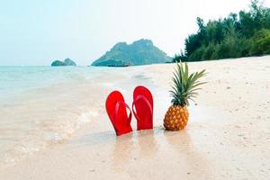 férias de verão na praia com abacaxis e chinelos na praia foto