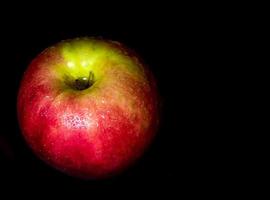 gota de água na superfície brilhante de maçã vermelha em fundo preto foto