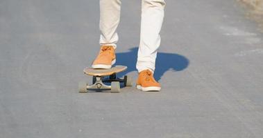 jovem passeio masculino no skate longboard na estrada rural em dia ensolarado foto