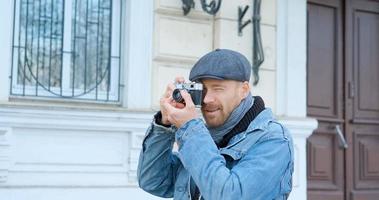 jovem viajante masculino bonito com câmera de filme faz fotos de rua