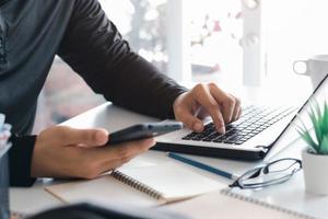 trabalho usando telefone celular digitando computador laptop de bate-papo móvel entre em contato conosco em locais de trabalho, planejando ideias investidores pesquisando na internet, ideias conectando pessoas. foto