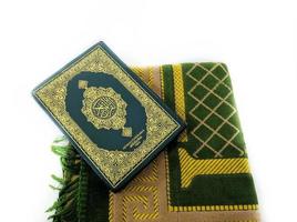fotos do Alcorão e tapetes de oração prontos para o Ramadã. árabe na capa é traduzido como o Alcorão