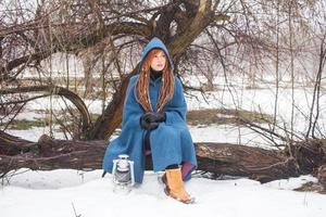 jovem de casaco azul retrô anda no parque nebuloso nos tempos de inverno, neve e fundo de árvores, fantasia ou conceito de fada foto