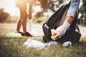 mão de mulher pegando plástico de lixo para limpeza no parque foto