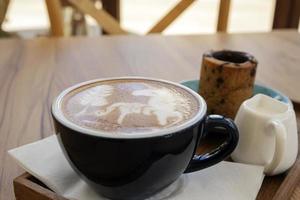 café com leite quente com biscoitos em uma mesa de madeira foto