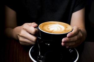 café com leite na mão. fundo escuro foto