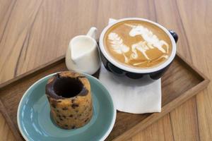 café com leite quente com biscoitos em uma mesa de madeira foto
