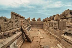 esculturas antigas nas paredes quebradas e arruinadas de um corredor dentro do templo da costa em mamallapuram em tamil nadu, índia. foto