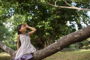 menina asiática bonitinha de pé entre o dia de sol do campo de flores roxas. liberdade desfrutando com a natureza. foto