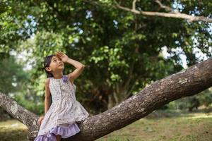 menina asiática bonitinha de pé entre o dia de sol do campo de flores roxas. liberdade desfrutando com a natureza. foto