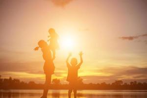mãe incentivou seu filho ao ar livre ao pôr do sol, conceito de silhueta foto