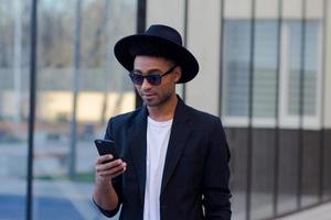 jovem macho feliz de terno preto e chapéu preto, conceito de empresário moderno foto