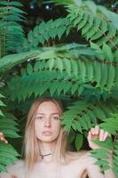 retrato de mulher jovem e bonita em folhas verdes, loira bonita em arbustos de primavera foto