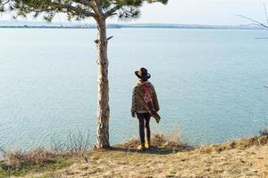 jovem viajante de mulher hipster de chapéu e poncho caminhando ao ar livre foto