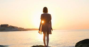 jovem de vestido relaxante na praia de verão durante o belo nascer do sol foto