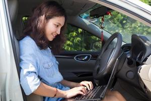 mulher asiática com um laptop no carro dela foto