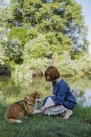 jovem em vestido retrô com cachorro corgi engraçado no piquenique foto