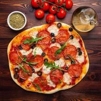 pizza de pepperoni italiana caseira quente com salame, mussarela e azeitonas foto