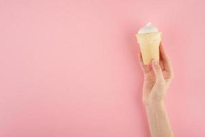 mão feminina segurando uma xícara de sorvete no espaço de cópia de vista superior de fundo rosa foto