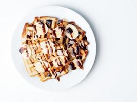 waffles de coalhada belga com framboesas, banana, calda de chocolate. café da manhã com chá no fundo branco, vista de cima, copie o espaço foto
