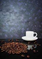 xícara de café e grãos de café em fundo escuro foto