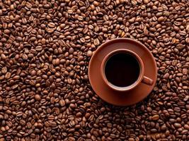xícara marrom de café expresso no fundo de grãos de café espalhados, vista superior, copie o espaço