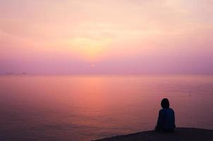 mulher de férias, olhando para o mar com bela vista à noite. pôr do sol na ilha, conceito de fundo romântico. foto