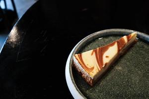 um pedaço de cheesecake de caramelo salgado servido em um prato redondo. bom gosto doce e delicioso. ae sobremesa que é perfeita para comer com café. foto