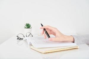 mulher escrevendo no caderno, conceito de trabalho de escritório no fundo da parede branca foto