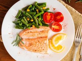peixe salmão cozido no vapor com legumes. comida de dieta saudável, pano de fundo de madeira escura