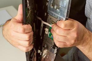 homem quebra o computador de mãos. rasga laptop em dois. o conceito de fadiga, estresse do escritório, burnout no trabalho foto