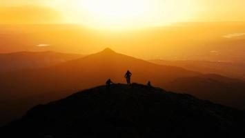 silhueta de ciclista de montanha no topo da colina ao pôr do sol foto