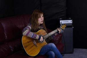 jovem mulher com guitarra canta no estúdio foto