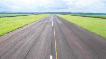 vista aérea da pista de avião pavimentada no brasil. pequena pista de pouso de aviões de hélice remota com plantação de cana-de-açúcar em segundo plano. foto