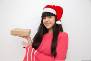 jovem mulher com gorro de papai noel segurando o presente de natal foto