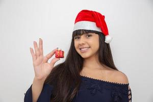 jovem mulher com gorro de papai noel segurando o presente de natal foto