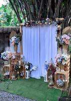 zona de fotos de casamento no país. decorações de casamento feitas à mão, incluindo flores vermelhas de cabine de fotos. buquês e lâmpadas