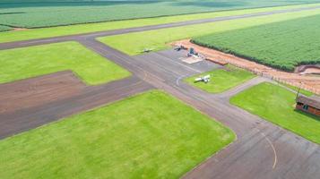 vista aérea da pista de avião pavimentada no brasil. pequena pista de pouso de aviões de hélice remota com plantação de cana-de-açúcar em segundo plano. foto