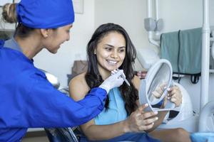 mulher bonita verificando os dentes após o tratamento. foto