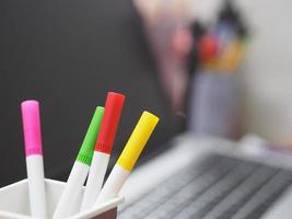 muitas caneta mágica cor vermelha, rosa, amarela, verde em caixa de plástico marrom, turva de fundo de notebook foto