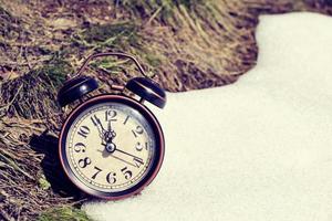 velho despertador retrô, grama e neve, simboliza a chegada da primavera ou do inverno. foto
