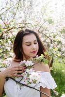 jovem mulher caucasiana, apreciando a floração de uma macieira foto