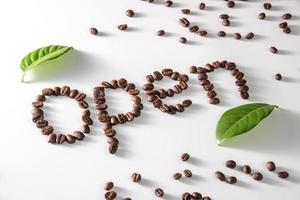 grãos de café em fundo branco com texto aberto feito de grãos de café. foto