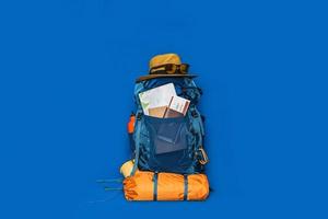 turismo planejando férias com a ajuda do mapa-múndi com outros acessórios de viagem ao redor. bagagem de conceito com acessório para férias de viajantes sobre fundo de cor azul. mochila de viagem foto