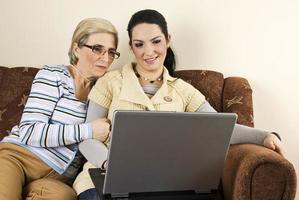 sorrindo duas mulheres com laptop em casa foto