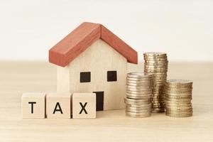 conceito de pagamento de impostos para habitação e propriedade. pagamento da dívida. modelo de casa, dinheiro e blocos de madeira com texto foto