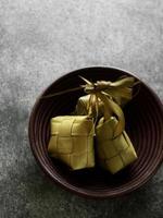 vista de ângulo superior de ketupat em uma tigela de bambu em cima da mesa foto
