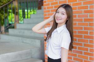 estudante asiática bonita está sorrindo e olhando para a câmera no fundo da universidade foto
