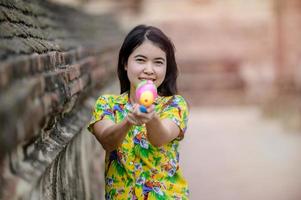 belas mulheres asiáticas seguram pistolas de água de plástico em um templo antigo durante songkran, o festival de água mais bonito e divertido da tailândia foto